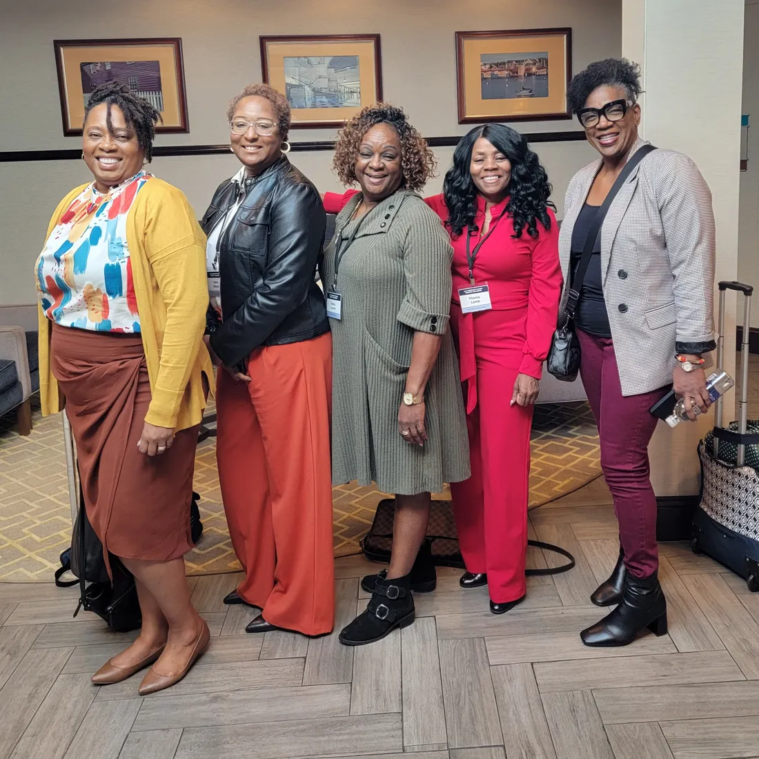 Five TBAH team members in colorful outfits pose together in a hotel lobby