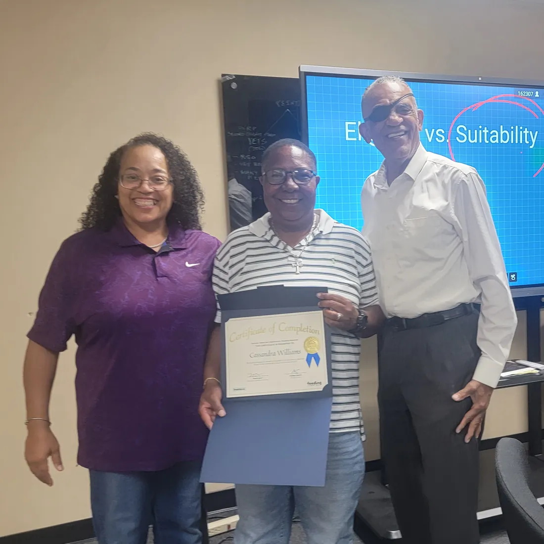 A program participant holds up his certificate between two TBAH staff members